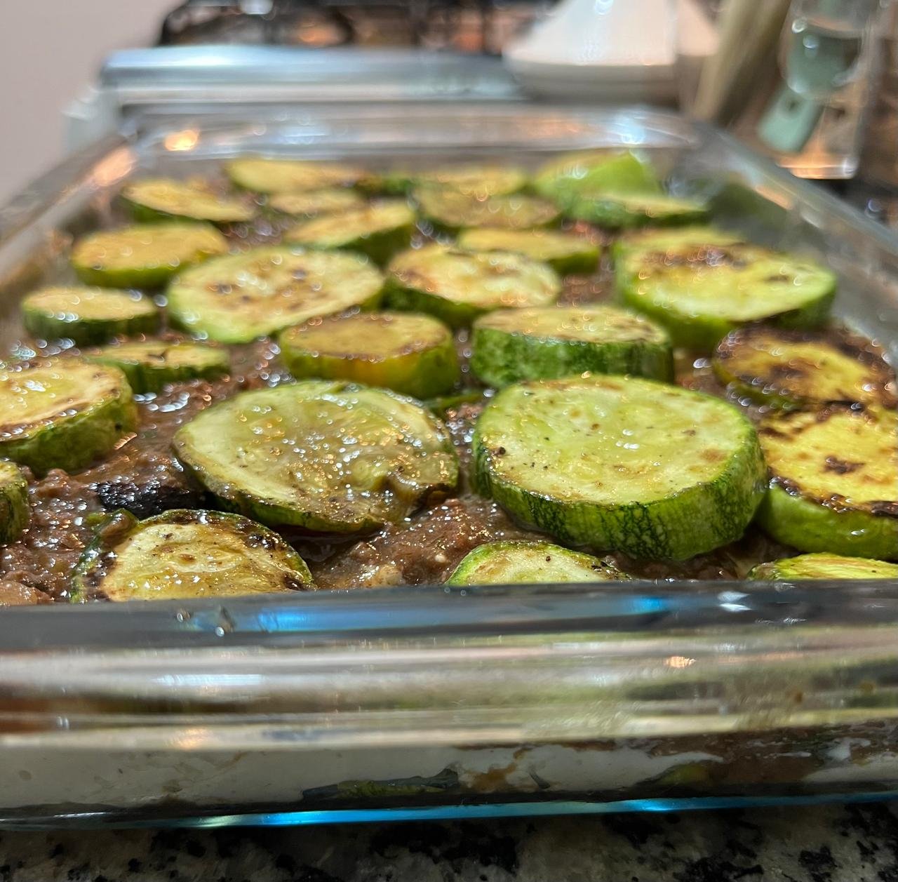 Camadas da abobrinha gratinada sendo montadas no refratário