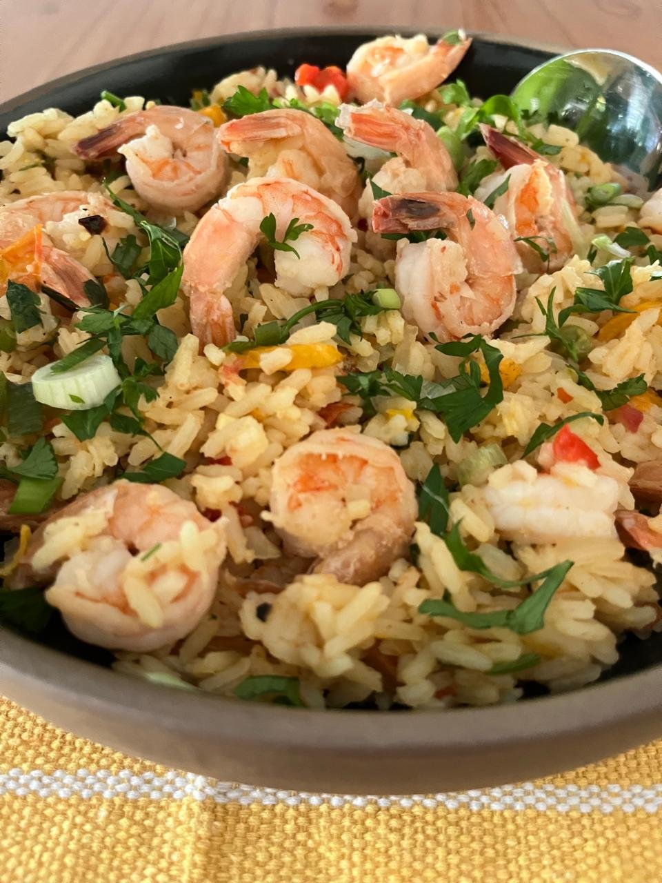 Arroz de camarão servido em bowl preto com salsinha fresca