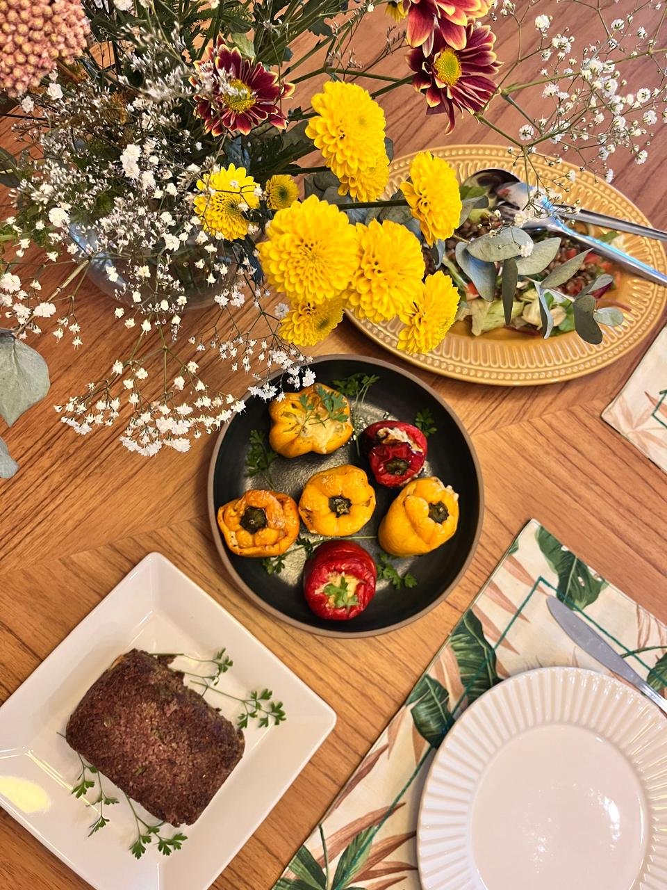 Pimentões coloridos recheados servidos à mesa com arranjo floral